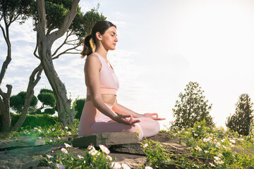 Meditates in nature. A girl is engaged in yoga on the street, in a pink tracksuit does various exercises and yoga poses