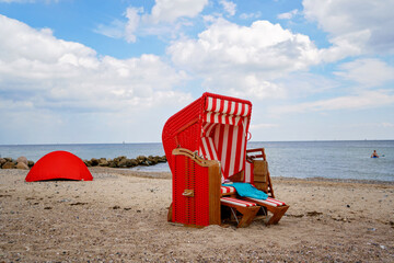 Traditional German roofed wicker beach chairs on the beach of Baltic Sea. Beach with red chairs on...