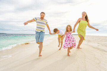  Young family on holiday have a lot of fun barefoot on the beautiful beach.