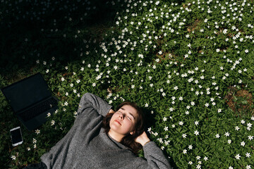Spring allergies. A beautiful young woman sneezing amidst a blooming flowers, symbolizing spring...