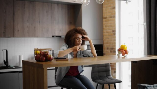 Tired African American woman drinking coffee at home, not having enough sleep
