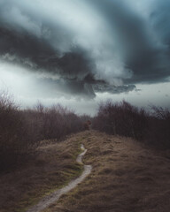 Winding trail leading towards a moody and cloudy sky