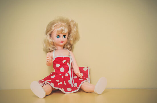 Retro kids plastic doll with blonde hair sitting on shelf.