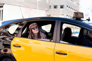 happy smiling girl discovering Barcelona through the window of the cab, stylish woman with a cap and sunglasses