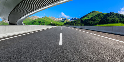 Fototapeta premium Asphalt road and bridge with green mountain background in Xinjiang, China.