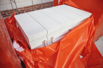 Autoclaved aerated blocks on concrete foundation, process of house building. Stacks of white...