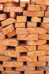 Stack of bricks close up. Process of house building and building materials concept. Red bricks for laying at construction site. Brick wallpaper pattern