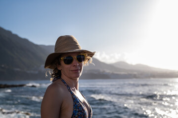 Frau steht mit und Sonnenbrille am Meer