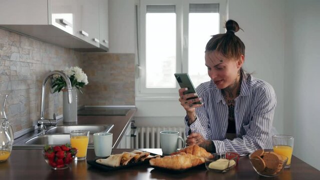 Attractive woman in her pajamas in kitchen using smartphone
