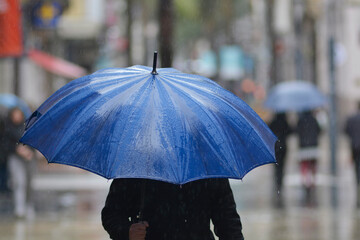 Persona con un paraguas azul bajo la lluvia