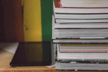 Stack of books next to a tablet on the bookshelf
