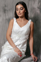 Girl in a wedding dress studio portrait on a gray background