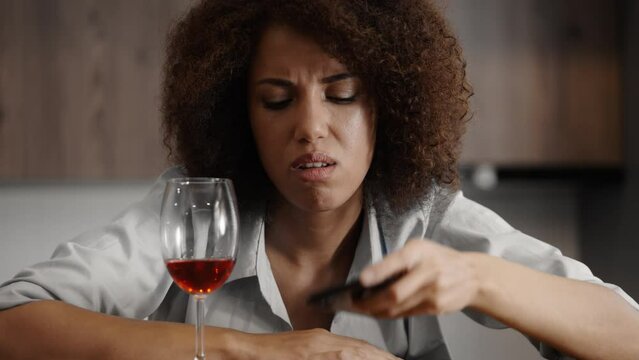 Displeased drunk woman calling her ex, drinking red wine, feeling lonely