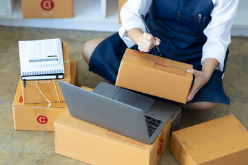 Startup SME small business entrepreneur of freelance Asian woman using laptop and box to receive and review orders online to prepare to pack sell to customers, online sme business ideas.
