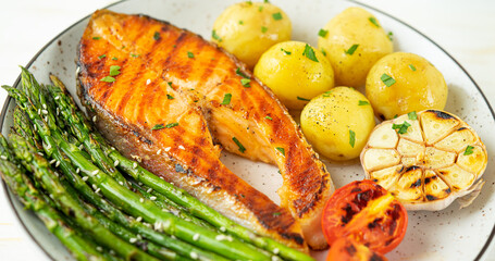 Plate of grilled trout steak, asparagus and potatoes with ingredients. Top view, close up