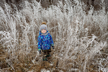 Frost covered all the bushes in the village in February. The smile of a happy 3-year-old child
