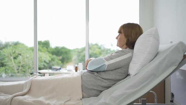Sick depressed lonely caucasian old elderly senior patient woman with splint. People sitting on bed at nursing home. Quarantine lifestyle. Unhappy life. Retirement community. Health care. Alone
