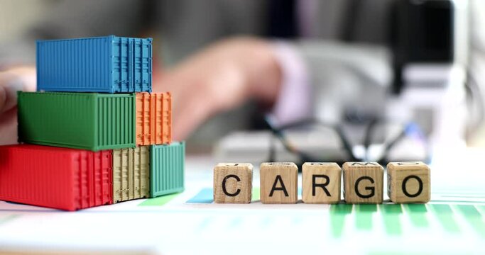 Business man moves stack of cargo containers on office table with financial documents