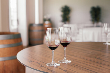 Two glasses of red wine on a wooden table in a bar with barrels 
