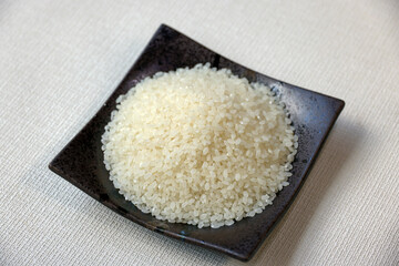 黒い角皿に盛られた一合の生米