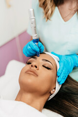 Professional cosmetologist making mesotherapy injection with dermapen on face for effective skin...