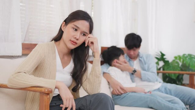 Asia woman sitting in the living room feeling stress after quarrel with husband. Father sits and hugs his son and encourages. Divorce law family problem concept. 