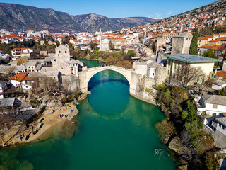 Fototapeta na wymiar Aerial drone view of the Old Bridge in Mostar city in Bosnia and Herzegovina during sunny day. Blue turquoise colors of Neretva river. Unesco World Heritage Site. People walking over the bridge.