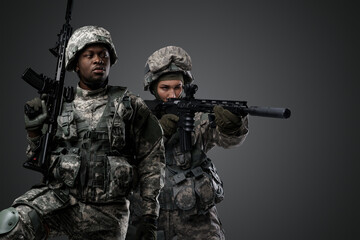 Studio shot of black soldier looking away and female comrade with rifle.