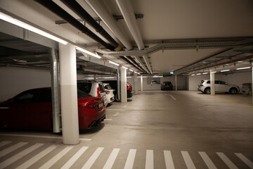 Underground parking for cars. Parking garage, interior with a few parked cars.