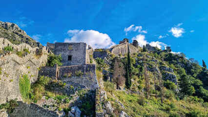Fototapeta premium Old medieval ruin of castle on Kotor city wall in Montenegro, Balkan Peninsula, Europe. Lovcen and Orjen mountains, Dinaric alps. Hiking trail to San Giovanni fortress. Historical landmark. Tourism