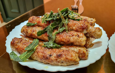 Close up view on grilled cevapcici with salvia in local restaurant on table in the city centre of...