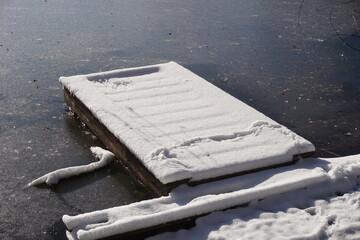 Wooden pier on lake covered with snow in winter