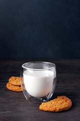 a glass of milk and oatmeal cookies on a dark background, a copy of the space, selective focus