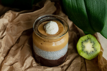Homemade pudding with granola, kiwi, grapes, coconut, flower leaf background