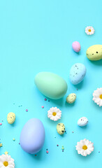 Easter holiday background with colorful easter eggs and white flowers on blue background. Top view from above.