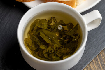 Green tea brewed in a mug and a baguette with chocolate butter