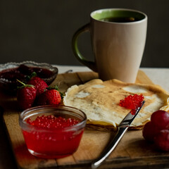 Pancake with red caviar for breakfast, a cup of tea