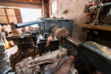 A senior man procesing wood on a lathe and making wooden dishes in the workshop