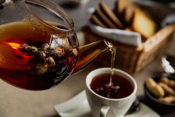 Girl pours black tea into a cup for breakfast
