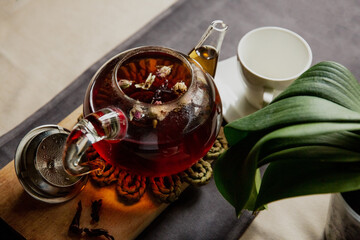 Black tea with rose flowers in a glass transparent teapot with a cup, beautiful breakfast