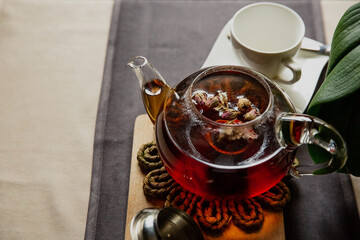 Black tea with rose flowers in a glass transparent teapot with a cup, beautiful breakfast
