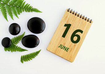 June 16. 16th day of the month, calendar date. Notepad, black SPA stoneJune s, green leaves. Summer month, day of the year concep