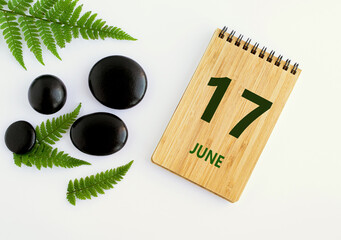 June 17. 17th day of the month, calendar date. Notepad, black SPA stoneJune s, green leaves. Summer month, day of the year concep