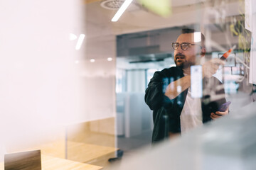 Confident male entrepreneur presenting ideas while drawing on glass board