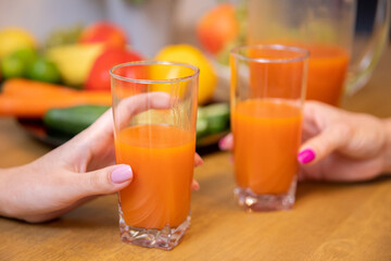 Close-up of two tall glasses of orange juice held in hands
