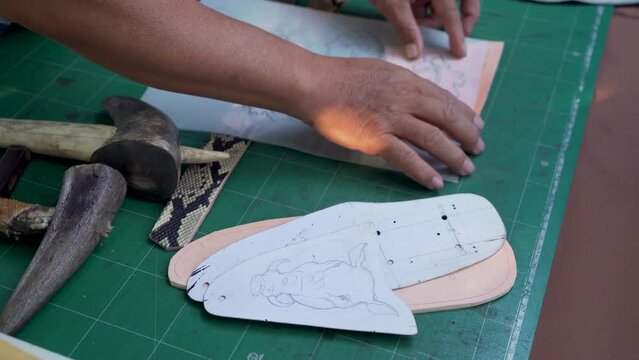 4K, Close-up hand holding glossy tracing paper with desired pattern, pressed into snakeskin in order get a pattern as it has been printed out, compare tracing paper same size as cut snakeskin.
