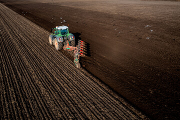 Aerial view of a tractor ploughing a fertile field with scavenging birds in flight © teamjackson
