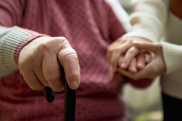 hands of an elderly woman lies on a wooden cane. The concept of the life of the elderly, caring for the elderly and accepting age