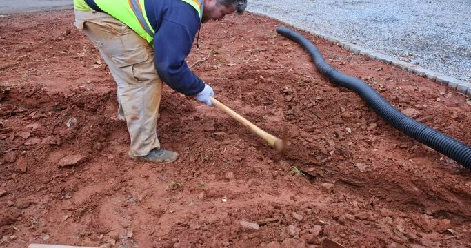 During major rainfall worker digs trench so as to lay drainage pipe for collect rainwater