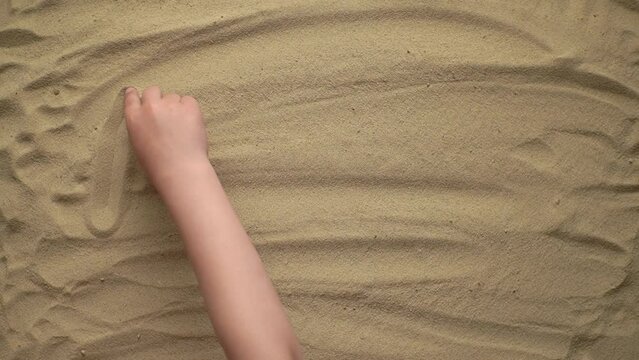 the child writes the word everything is all right with his finger on the yellow sand. slow motion video. High quality Full HD video recording